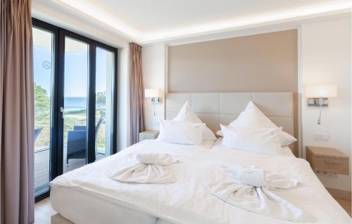 ein weißes Bett in einem Zimmer mit einem großen Fenster in der Unterkunft Prince in Binz