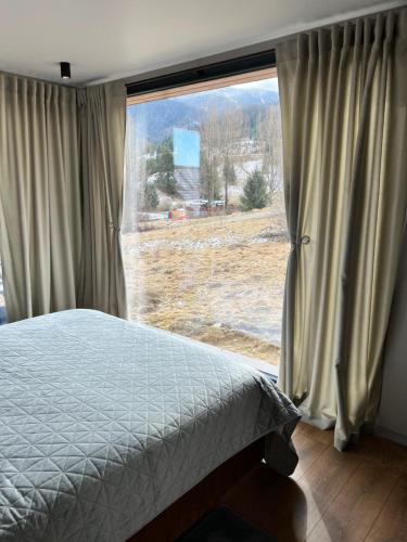 a bedroom with a bed and a large window at The kube by the mountain in Timisul de Jos