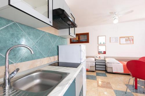 a kitchen with a sink and a room with a bed at Apartmani Margita in Mošćenička Draga