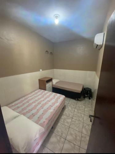 1 dormitorio pequeño con 2 camas y mesa en Flat da Tássia, en Maragogi