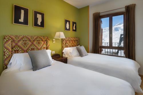 福米加尔Montesqui Formigal, exclusivo ático con vistas a pistas, guardaesquis y garaje的有两张床和一扇窗户的酒店房间