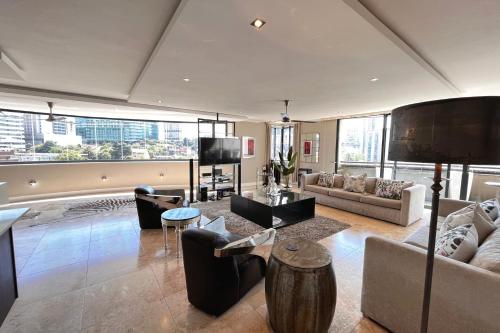 a living room filled with furniture and a large window at Luxury Penthouse In The Heart Of Sandton in Johannesburg