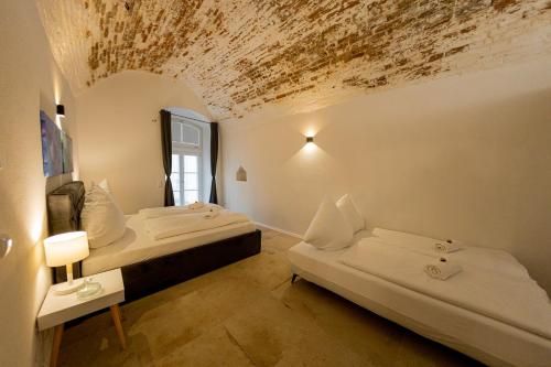 two beds in a room with a ceiling covered in dirt at Servus Apartments Old Town Premium in Passau