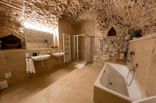 a stone bathroom with a tub and a sink at Servus Apartments Old Town Premium in Passau