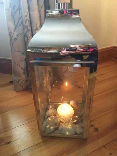 a candle in a glass container on the floor at Skelligway Kenmare - Your Luxury Holiday Home in Kenmare