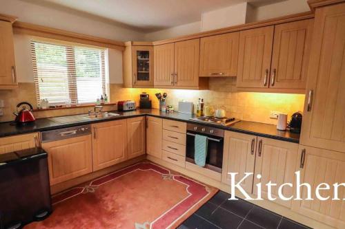 a kitchen with wooden cabinets and a red rug at Skelligway Kenmare - Your Luxury Holiday Home in Kenmare