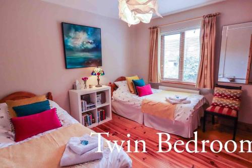 a bedroom with two beds and a window at Skelligway Kenmare - Your Luxury Holiday Home in Kenmare