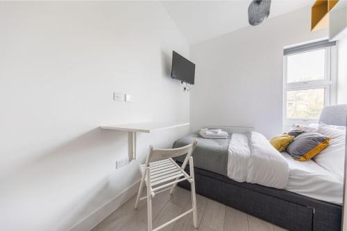 a bedroom with a desk and a bed with a chair at Functional Budget Stay with Wi-Fi and Laundry Facilities near Tube Station in London