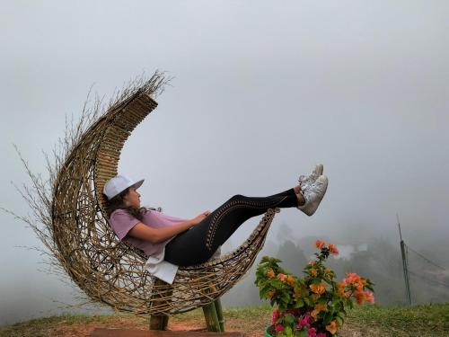 a woman is sitting in a wicker chair at El Mirador de Guatape APTO in Guatapé