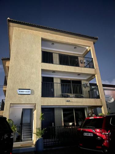 ein Gebäude mit einem Balkon und einem Auto vor dem Haus in der Unterkunft Nuben Court-Accra in Accra