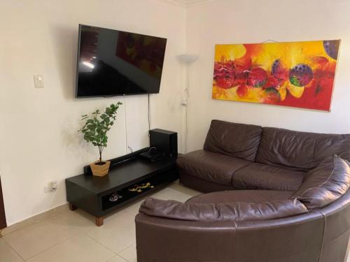 a living room with a couch and a flat screen tv at Bellomar I Exclusive Juan Dolio Playa Hemingway in Juan Dolio