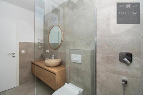 a bathroom with a sink and a toilet and a mirror at VILLA LJUBAS in Srima