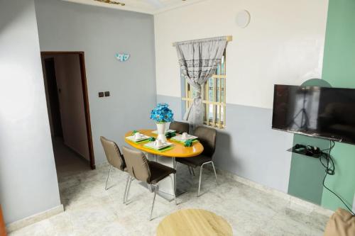 a dining room with a table and chairs and a television at Le Doux Refuge in Djérigbé