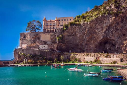 ein Schloss an der Seite eines Berges mit Booten im Wasser in der Unterkunft La Rosa dei Venti - Libeccio in Maiori