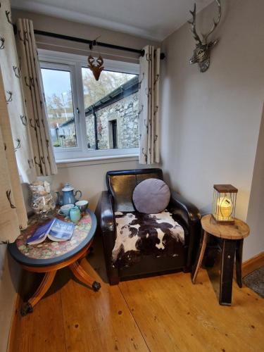 a living room with a chair and a table at Fyne Byre Cottage - Barn Conversion with Hot Tub in Cairndow