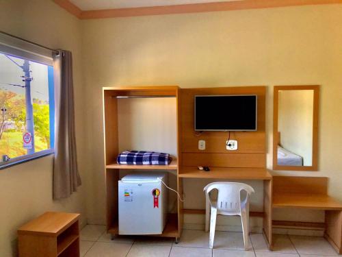 a room with a desk with a computer and a refrigerator at Santa Catarina Hotel in Aparecida