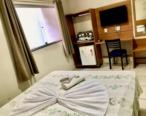 a bed with a bow on it in a room at Santa Catarina Hotel in Aparecida