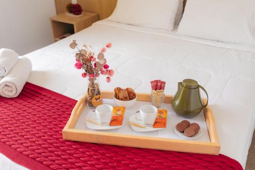 a tray with coffee cups and pastries on a bed at Pousada Relicário in Tiradentes