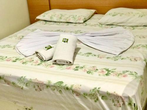 een bed met witte lakens en roze bloemen erop bij Santa Catarina Hotel in Aparecida