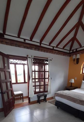 a bedroom with a bed and two windows at Hotel Bosque de la Villa in Villa de Leyva