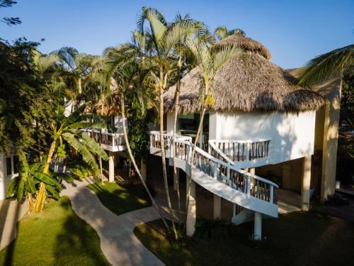 a building with a thatched roof with palm trees at Hotel Ysuri San Pancho in San Francisco