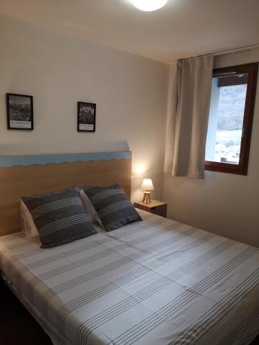 une chambre avec un grand lit avec une fenêtre dans l'établissement Les Balcons de La Neste - Appt 1 à 6 personnes (Balcon et vue montagne), à Arreau