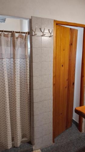 uma casa de banho com uma cortina de chuveiro e uma porta em Hostal del río em El Bolsón