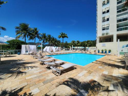 a swimming pool with lounge chairs and a building at Apart Hotel Alecrim Praia de Camboinhas com Marina pe na areia in Niterói