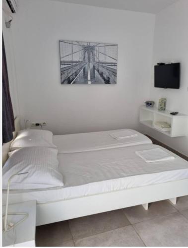 - un lit blanc dans une chambre avec une photo sur le mur dans l'établissement White pearl, à Sukošan