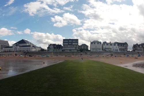 un groupe de personnes sur une plage avec des bâtiments dans l'établissement 2 pièces ensoleillé accès direct plage, à Cabourg