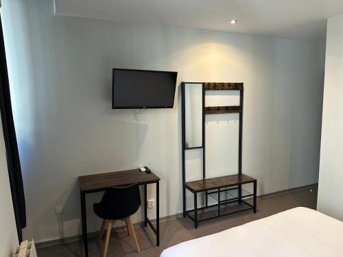 - une chambre avec une télévision, une table et un miroir dans l'établissement Hôtel Beauséjour, à Marseille