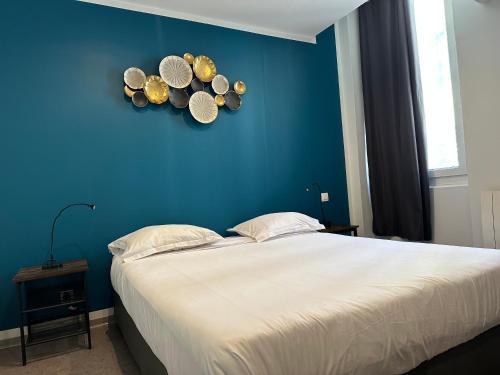 Un dormitorio con una pared azul y una cama con sombreros en la pared en Hôtel Beauséjour en Marsella