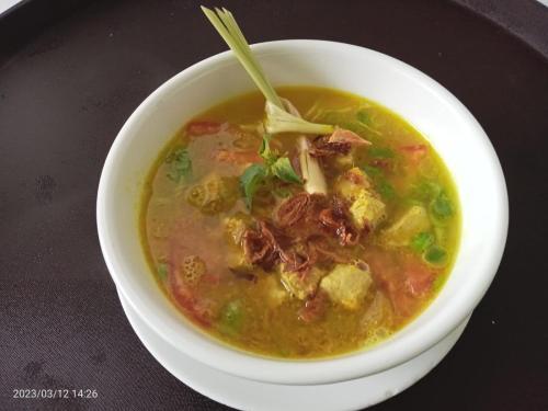 a bowl of soup on a table with a spoon at Devanora Hotel & Resto in Kintamani
