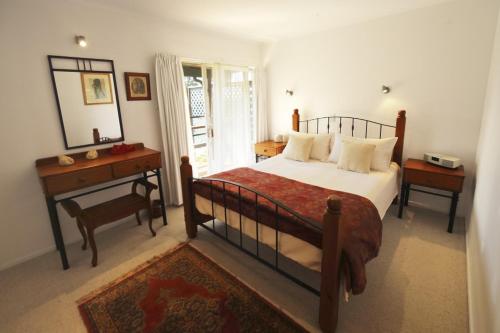 a bedroom with a bed and a table and a mirror at Selwyn Cottage in Burnt Pine