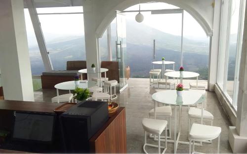 a room with tables and white chairs and a tv at Devanora Hotel & Resto in Kintamani