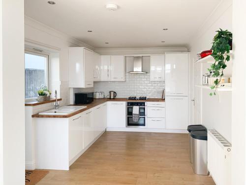 a white kitchen with wooden floors and white cabinets at Panorama Apartment 1 - Uk40626 in Southbourne