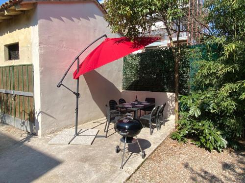 een tafel en stoelen met een rode parasol en een grill bij GARDALAND Residenza le Rose! 120 m2 in Valeggio sul Mincio