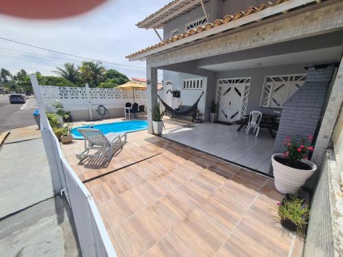 una terraza de madera con sillas y una piscina en Casa cinza em frente à praia em condominio, en Aracaju