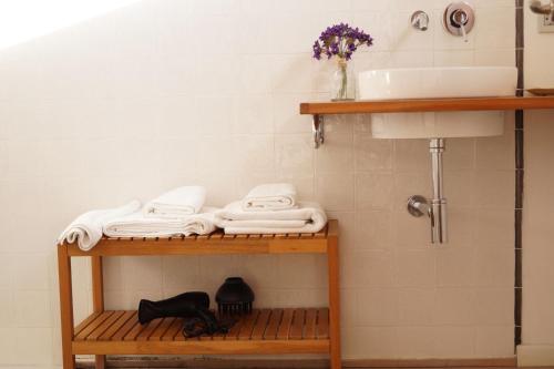 Baño con estante con toallas y lavamanos en Hotel El Patiaz de la Reina Rana en Tauste