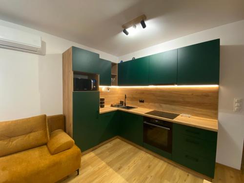 a kitchen with green cabinets and a couch at Apartament Spokojna Przystań in Rzeszów