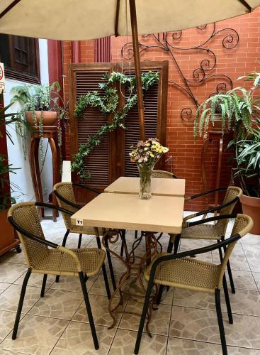 a table and chairs with a vase of flowers on it at Lima Wari Hotel Boutique in Lima