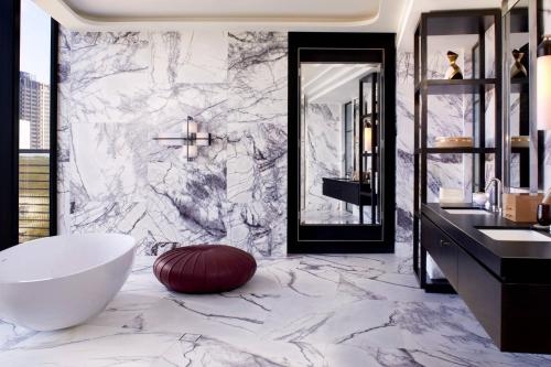 a bathroom with a white tub and a marble wall at The Ritz-Carlton, Perth in Perth