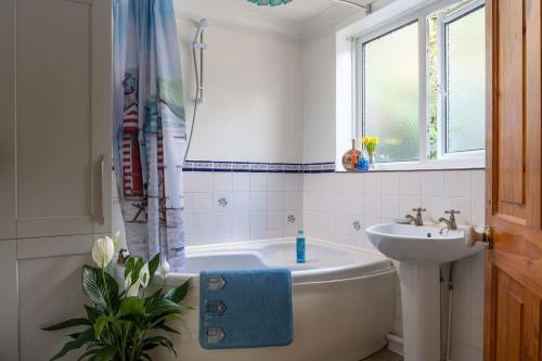 a bathroom with a white tub and a sink at Alma's Cottage at Penmaenmawr in Penmaen-mawr