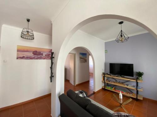 a living room with a couch and a tv at Apartamento Vicentino in Vila Nova de Milfontes