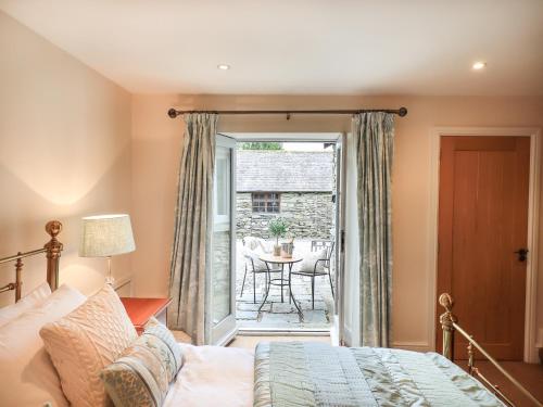 a bedroom with a bed and a patio with a table at Hart Head Barn in Ambleside