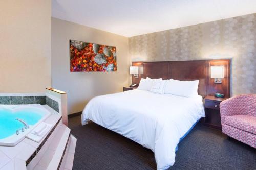 a hotel room with a large bed and a tub at Courtyard Marriott Lake Placid in Lake Placid