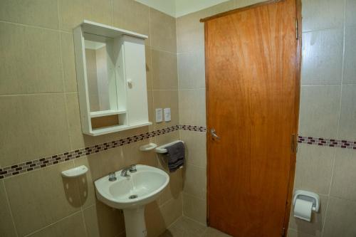 a bathroom with a sink and a wooden door at Las Moras Del Manantial in Termas de Río Hondo