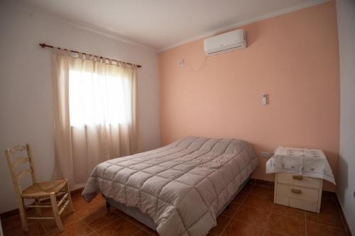 a bedroom with a bed and a window and a chair at Las Moras Del Manantial in Termas de Río Hondo