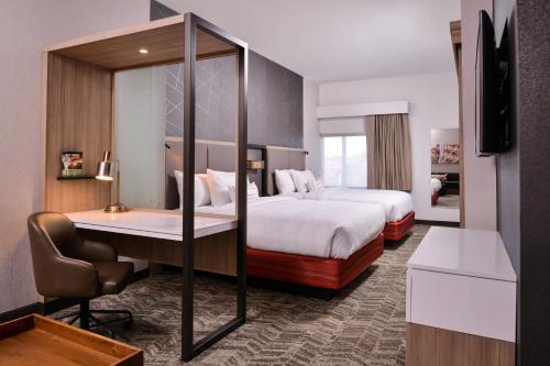 um quarto de hotel com uma cama e uma secretária com uma cadeira em SpringHill Suites by Marriott Greensboro Airport em Friendship