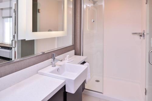 a white bathroom with a sink and a shower at SpringHill Suites by Marriott Greensboro Airport in Greensboro